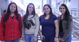 Em pé, estudantes estão de frente, e a foto está em plano aberto