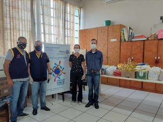 Várias pessoas posando ao lado de um banner. Atrás delas, vários alimentos.