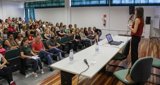 Uma mulher palestrando para auditório lotado