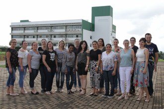 Várias pessoas, lado a lado, posando para a fotografia. Ao fundo, prédio da UFFS.