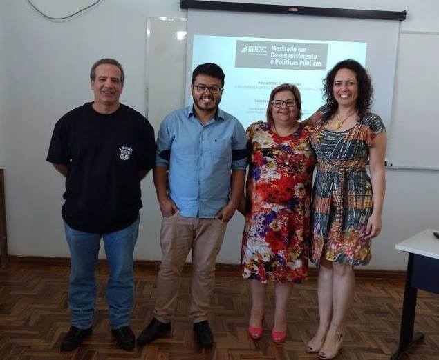 Quatro pessoas, uma ao lado da outra, em uma sala de aula olhando para a câmera.