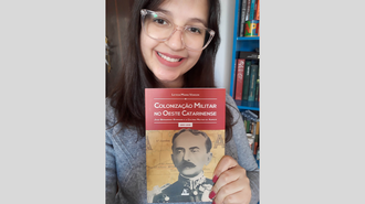 Foto de Leticia, na qual ela aparece olhando para a câmera, em ângulo fechado no seu rosto. Ela segura seu livro.