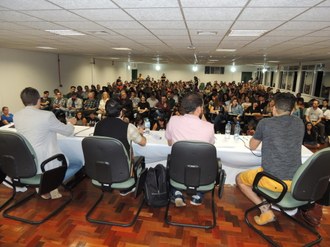 Foto com os professores do evento na mesa de honra, com a plateia na frente