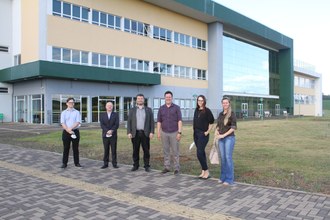 seis pessoas posam para a foto na frente de um prédio do campus