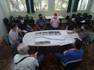 Foto aparecendo pessoas reunidas em torno de mesa