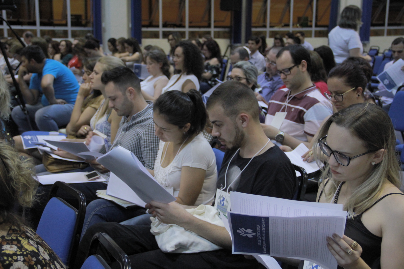 Pessoas sentadas lendo os papeis que integram o manifesto Saúde e democracia: desafios para o Brasil contemporâneo