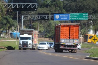 a imagem é uma estrada onde há placas de sinalização "rodovia br 282" e há carros e caminhões na estrada